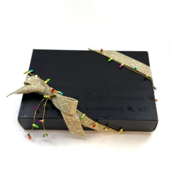 Geschenkband, Faux light Kordel in gold mit farbigen kleinen Tannenbaumlichter an einer schwarzen Geschenkbox